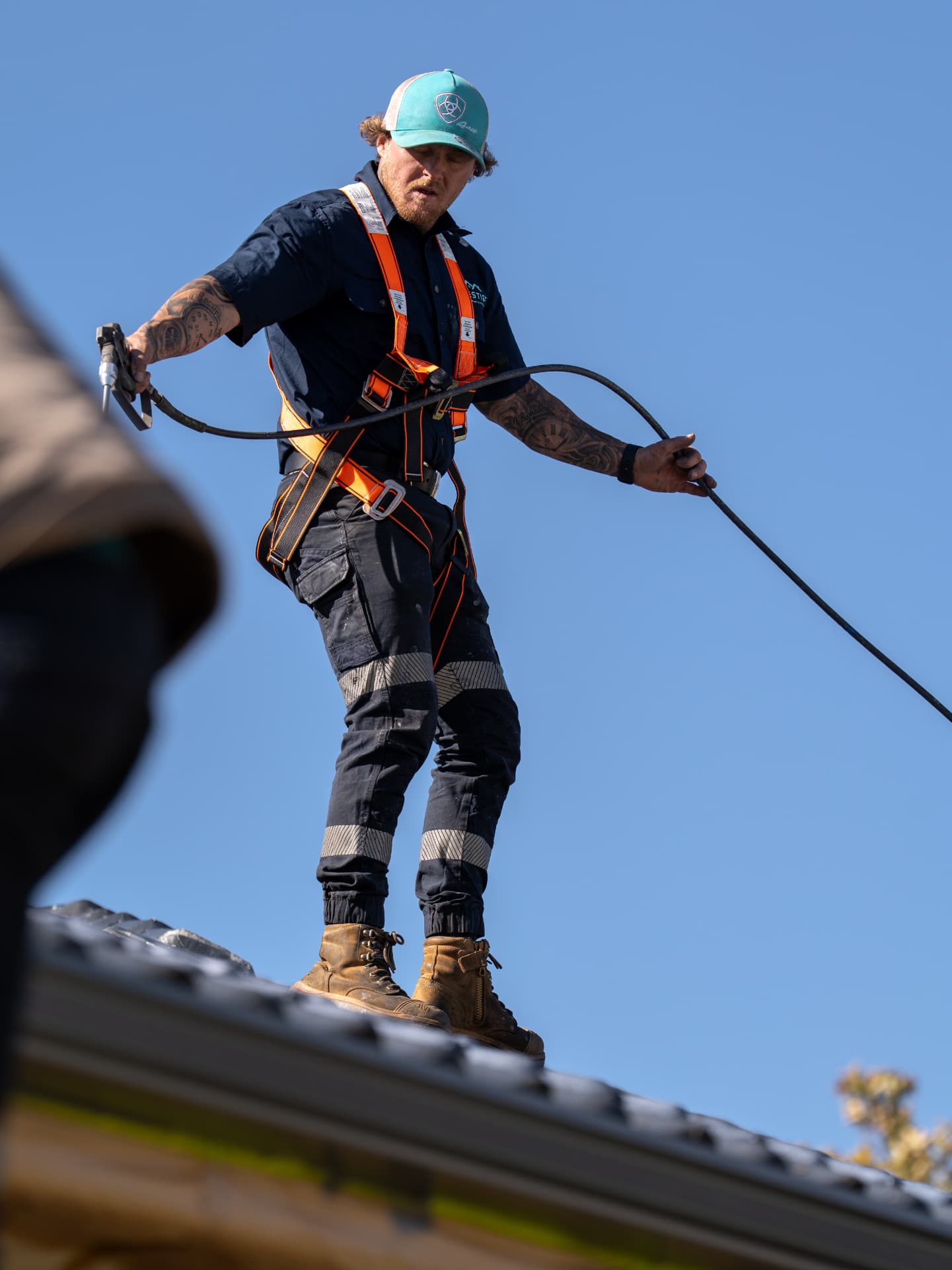 Prestige tradesman spraying a roof in a safety harness